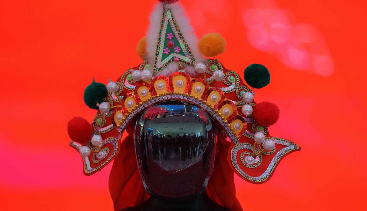 Sebuah robot humanoid yang mengenakan hiasan kepala tradisional dipamerkan selama pratinjau media pameran kuil robot menjelang Tahun Baru Imlek di Beijing, China, Jumat 13 Februari 2026. (AP Photo/Vincent Thian)
