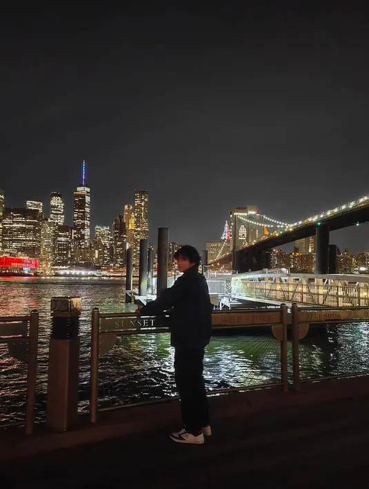 Tak puas menikmati kota New York sambil duduk, Angga Yunanda pun berdiri sambil bersandar di panggar pembatas sungai. (Foto: Instagram/@anggayunandareal16)