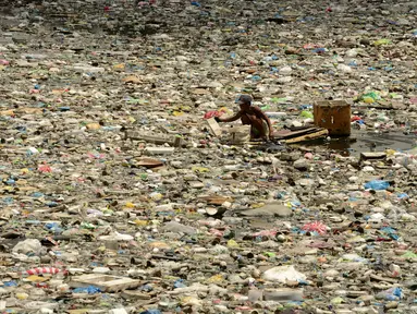 Teresita Gapayao (51) mengais sampah menggunakan rakit yang terbuat dari stereofoam di aliran Sungai Estero de Vitas di Tondo, Manila, Filipina, Kamis (21/4). Teresita mengumpulkan botol plastik atau apapun yang bisa dijual ke junkshops. (Noel CELIS/AFP)