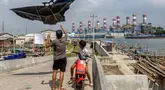 Anak-anak menerbangkan layang-layang saat bermain di sepanjang tanggul laut yang dibangun di desa pesisir Tambaklorok, di Semarang, Jawa Tengah, pada 17 Juni 2025. (DEVI RAHMAN/AFP)