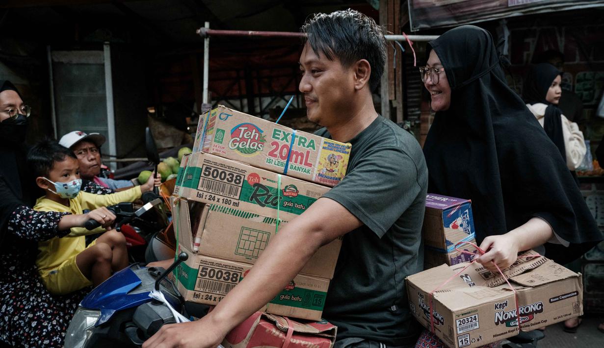 Airlangga mengungkap pemerintah juga telah menyalurkan bantuan sosial senilai hampir Rp 30 triliun sebagai salah satu upaya memperkuat daya beli masyarakat. Tampak dalam foto, seorang pria memegang kotak-kotak di antara lengannya sambil mengendarai motor setelah berbelanja di kios pinggir jalan di Jakarta pada Sabtu 8 November 2025. (YASUYOSHI CHIBA/AFP)