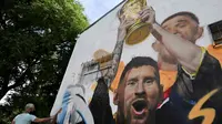 Seniman Maxi Bagnasco melukis mural yang menggambarkan kapten dan penyerang Argentina Lionel Messi mengangkat Trofi Piala Dunia 2022 di samping rekan satu timnya setelah memenangkan turnamen Piala Dunia Qatar 2022 di Buenos Aires pada 22 Desember 2022. (AFP/Luis Robayo)