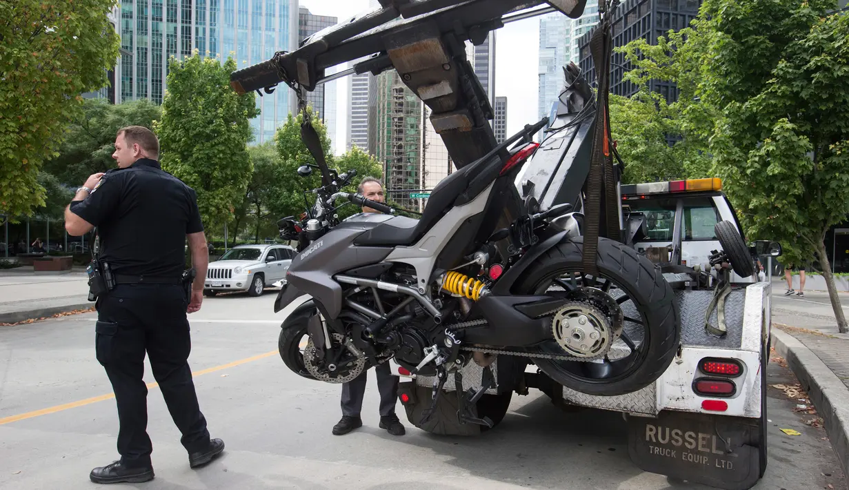 Petugas membawa motor Stuntwoman yang mengalami kecelakaan saat syuting film "Deadpool 2" di set, di Vancouver, BC, (14/8). Stuntwoman yang diketahui bernama SJ Harris meninggal saat mengendarai motor. (Darryl Dyck / The Canadian Press via AP)