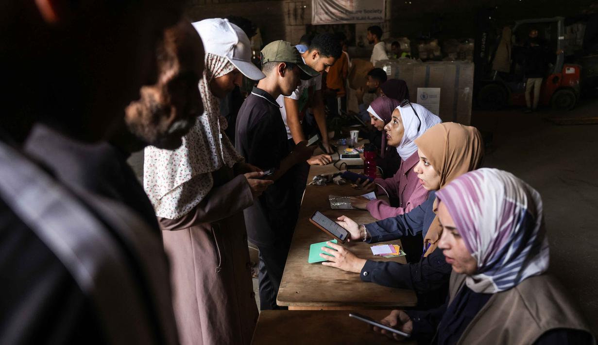 Warga Palestina dari Jalur Gaza diperiksa identitasnya saat tiba di pusat distribusi untuk mengambil kotak bantuan makanan yang disediakan oleh Program Pangan Dunia (WFP), di desa Al-Zawayda, di tengah Jalur Gaza pada 27 Oktober 2025. (BASHAR TALEB/AFP)