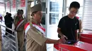 Petugas membantu penumpang untuk memasuki Trans Jakarta, Selasa (16/8). Petugas mengenakan pakaian tentara perjuangan tempo dulu untuk menyambut para penumpang. (Liputan6.com/Angga Yuniar)