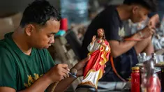 Para pekerja menyemprotkan cat ke patung-patung rohani di bengkel kerajinan Studio Malta Jaya di Bantul, Yogyakarta, pada Kamis 18 Desember 2025. Jelang perayaan Natal 2025, kesibukan terlihat di bengkel kerajinan Studio Malta Jaya di Bantul, Yogyakarta. (DEVI RAHMAN/AFP)