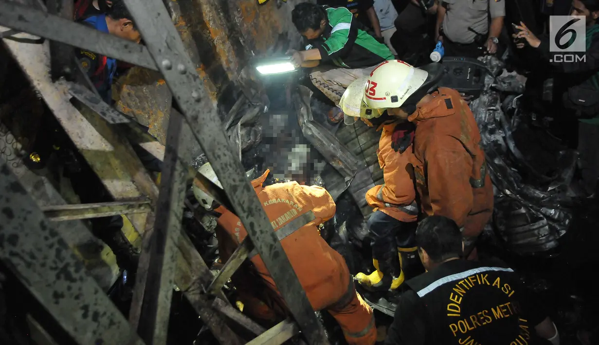 Petugas menemukan dua jasad yang sudah hangus terbakar di dalam puing minibus yang ringsek usai  kecelakaan kereta api di perlintasan Kramat, Senen, Jakarta, Selasa (13/6). (Liputan6.com/Helmi Afandi)