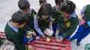 Anak-anak Tibet di pengasingan berbagi makan siang mereka saat istirahat di kelas di Sekolah Hari Desa Anak-anak Tibet di Dharmsala, India (24/3/2022). Kehidupan sekolah perlahan kembali normal setelah sempat terganggu akibat pandemi COVID-19. (AP Photo/Ashwini Bhatia)