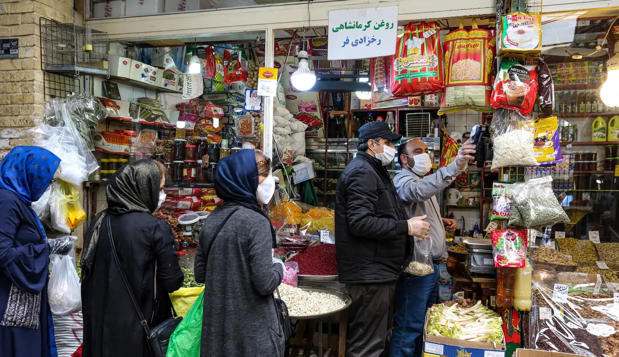 Pedagang mengenakan masker wajah dan sarung tangan lateks, karena pandemi virus corona COVID-19, melayani pembeli selama bulan suci Ramadan di pasar Tajrish, Taheran, Iran (25/4/2020). (AFP/Atta Kenare)