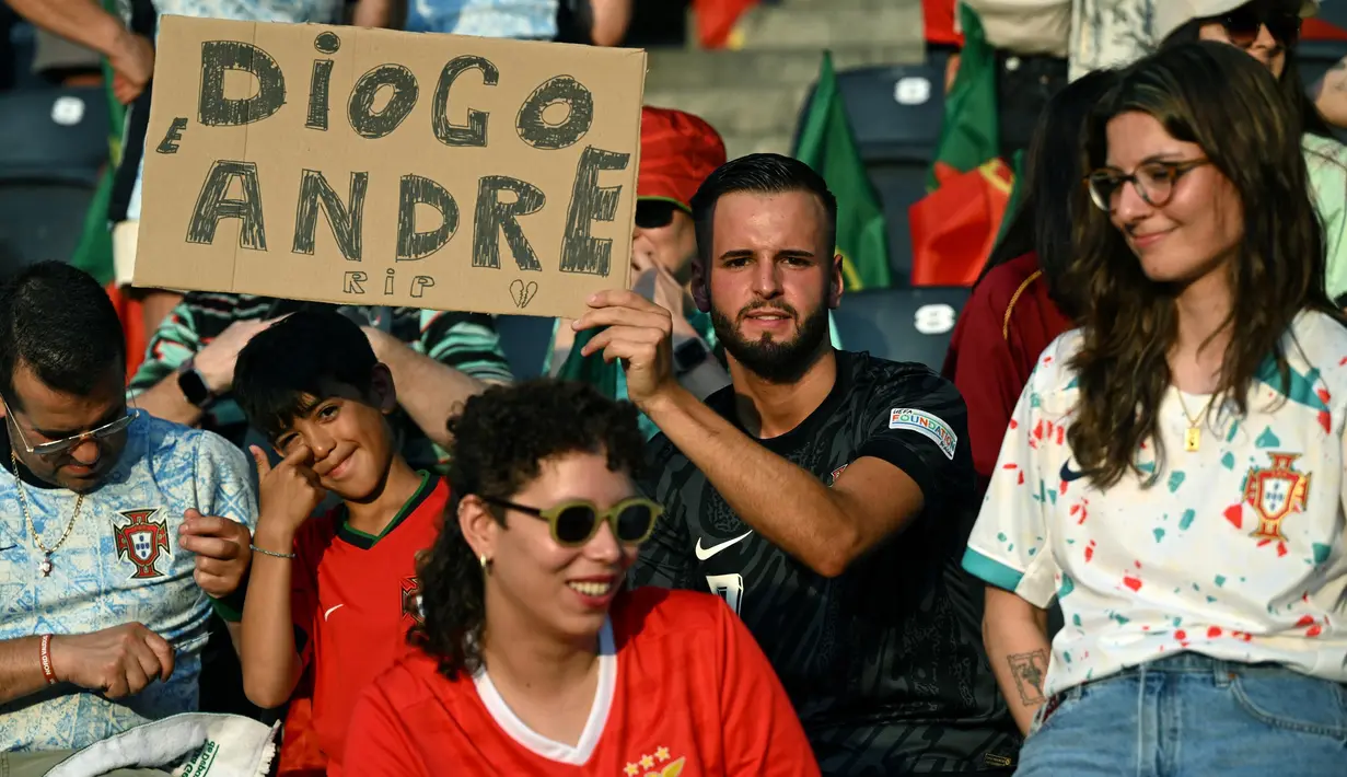 Diketahui, Diogo Jota yang berusia 28 tahun ini baru saja melangsungkan pernikahan dengan tunangannya, Rute Cardoso, pada 22 Juni 2025 lalu. Tampak dalam foto, para penggemar memegang tulisan saat mereka memberikan penghormatan kepada penyerang Liverpool asal Portugal, Diogo Jota, menjelang pertandingan sepak bola UEFA Women's Euro 2025 Grup B antara Spanyol dan Portugal di stadion Wankdorf di Bern, Jerman pada 3 Juli 2025. (Miguel MEDINA/AFP)