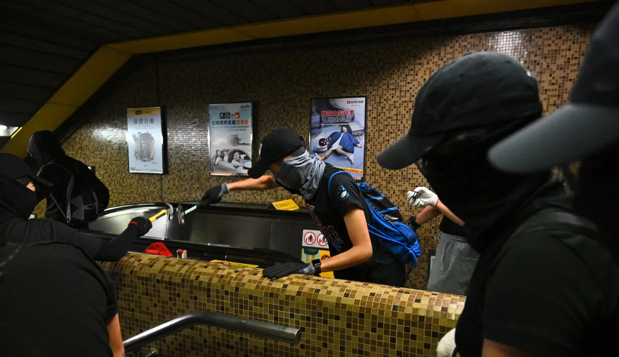 Sejumlah demonstran bertopeng merusak Stasiun MTR Wong Tai Sin di Distrik Kowloon, Hong Kong, Senin (7/10/2019). Eskalasi kerusuhan di Hong Kong semakin membesar setelah pemerintah mengeluarkan larangan demonstrasi menggunakan masker atau UU Antitopeng. (Philip FONG/AFP)