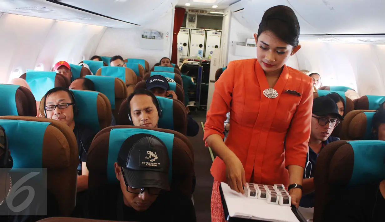 Pramugari membagikan cokelat kepada penumpang dalam penerbangan di Pesawat Garuda Indonesia menuju, Padang, Sumatera Barat, Jumat (21/4). Menyambut Hari Kartini, penerbangan Garuda Indonesia diawaki seluruhnya oleh perempuan. (Liputan6.com/Angga Yuniar)