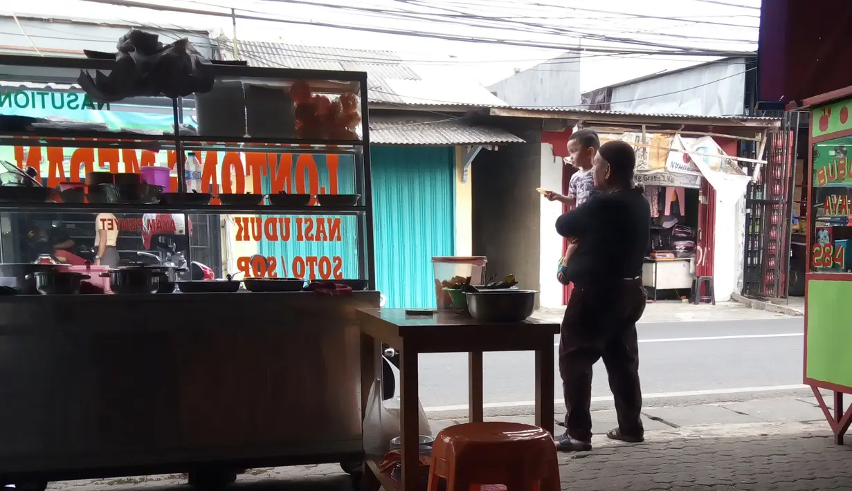 Di sisi lain, pria berbaju hitam beserta pecinya itu juga terlihat begitu bahagia ketika berjualan sambil bercengkrama dengan sang cucuk. Di tengah kesibukannya, Hamzah tetap sempat bermain dengan cucunya. (Nurwahyunan/Bintang.com)