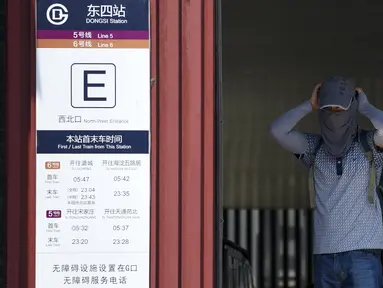 Seorang pria mengenakan penutup wajah untuk menghadapi teriknya panas matahari di stasiun kereta bawah tanah di Beijing, Rabu (12/7).Sebanyak 21 provinsi di China diterpa gelombang panas dengan suhu maksimum mencapai 50 derajat Celsius. (WANG ZHAO/AFP)