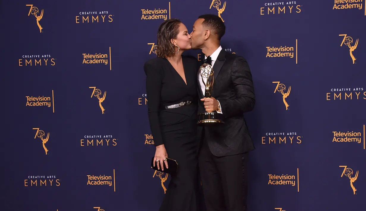 Chrissy Teigen dan John Legend berciuman di karpet merah selama Creative Arts Emmy 2018 di Microsoft Theater di Los Angeles, California, AS (9/9). John Legend mendapatkan penghargaan di acara tersebut. (AFP Photo/Alberto E. Rodriguez)