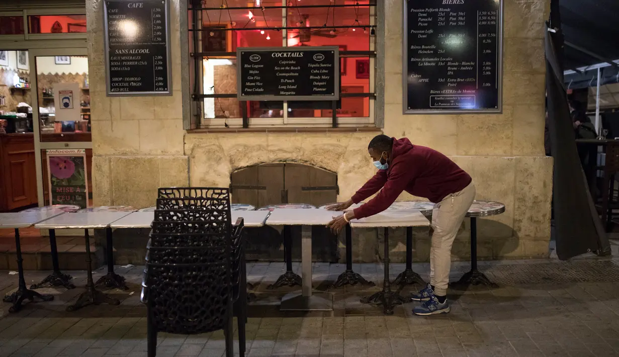 Seorang pramusaji menutup teras bar di Marseille, selatan Prancis, Minggu (27/9/2020). Restoran dan bar di Marseille pada hari Minggu bersiap tutup selama sepekan sebagai bagian dari pembatasan baru baru Covid-19. (AP Photo/Daniel Cole)