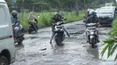 Pengendara motor berusaha menghindari jalan rusak yang menjadi kubangan air di Jalan Raya Gas Alam, Depok, Jawa Barat, Selasa (7/5). Kondisi jalan yang tidak kunjung diperbaiki tersebut menjadi kubangan air setiap hujan serta berbahaya bagi keselamatan pengguna jalan (Liputan6.com/Immanuel Antonius)