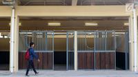 Pewarta melintas di depan istal di kawasan Jakarta International Equestrian Park Pulomas, Jakarta, Kamis (2/8). JIEPP akan menjadi venue tiga cabang equestrian Asian Games 2018. (Liputan6.com/Helmi Fithriansyah)