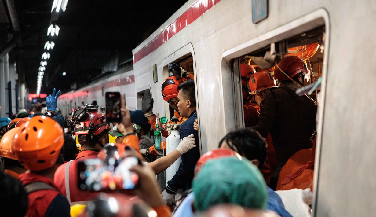 Tim pencari dan penyelamat gabungan berupaya menyelamatkan salah satu korban yang terjebak di dalam gerbong setelah lokomotif Kereta Api Jarak Jauh (KAJJ) Argo Bromo Anggrek menabrak gerbong belakang Kereta Rel Listrik (KRL) Commuter Line di stasiun Bekasi Timur, Bekasi, Jawa Barat pada Selasa 28 April 2026. (Yasuyoshi Chiba/AFP)