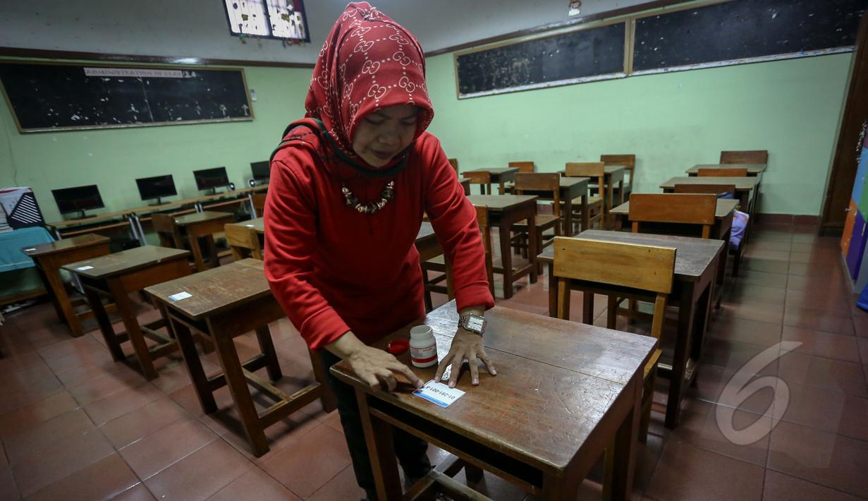 Guru memasang daftar nomor peserta di ruangan kelas SDN 01 Menteng, Jakarta, Minggu (17/5/2015). Sejumlah sekolah melakukan persiapan menjelang Ujian Nasional (UN) jenjang SD/MI yang berlangsung pada 18-20 Mei mendatang. (Liputan6.com/Faizal Fanani)
