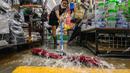 Seorang pekerja membersihkan air dari tokonya di Pasar Namseong yang bersejarah di distrik Gangnam Seoul (9/8/2022).  Hujan yang turun sangat deras pada Senin malam (8/8/2022) menyebabkan banjir parah yang memecahkan rekor dengan sedikitnya tujuh orang tewas dan tujuh lainnya hilang, kata para pejabat. (AFP/Anthony Wallace)