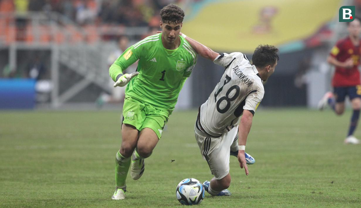 Pemain Timnas Jerman U-17, Bilal Yalcinkaya (kanan), terjatuh setelah mendapatkan gangguan dari kiper Timnas Spanyol U-17, Raul Jimenez, saat pertandingan perempat final Piala Dunia U-17 2023 yang berlangsung di Jakarta International Stadium, Jumat (24/11/2023). (Bola.com/Arief Bagus)