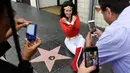 Penggemar mengenakan kostum Wonder Woman berpose di bintang Hollywood Walk of Fame aktris Lynda Carter di Los Angeles (3/4). Lynda Carter merupakan aktris yang memerankan serial televisi Wonder Woman tahun 1970-an. (Chris Pizzello / Invision / AP)