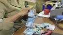 Pegawai tengah menghitung mata uang rupiah di penukaran uang di Jakarta, Rabu (4/3/2020). Rupiah ditutup menguat 170 poin atau 1,19 persen menjadi Rp14.113 per dolar AS dibandingkan posisi hari sebelumnya Rp14.283 per dolar AS. (Liputan6.com/Angga Yuniar)
