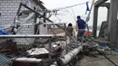 Warga berjalan diantara tiang lampu listrik yang berserakan di jalan akibat tornado yang menyapu wilayah Yancheng, Provinsi Jiangsu, Tiongkok, Kamis (23/6). Badai disertai hujan es telah menyebabkan kekacauan di Jiangsu. (STR/AFP)