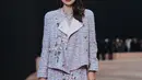 Rebecca Amstrong tampil borjuis dengan setelan open lid jacket dan rok mini tweed bermotif bunga. Ia terlihat jinjing Flap Bag mini silver sebagai aksesori [Chanel]