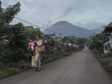 Gunung Semeru menjulang di atas desa Lumajang, Jawa Timur, setelah meletus sehari sebelumnya, Minggu (17/1/2021). Gunung Semeru kembali erupsi dan mengeluarkan awan panas guguran sejauh 4,5 kilometer pada Sabtu (16/1). (Juni Kriswanto / AFP)