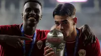 Selebrasi pemain Timnas Indonesia U-19, Jens Raven (kanan) bersama Meshaal Hamzah dengan mencium trofi juara Piala AFF U-19 2024 usai mengalahkan Thailand U-19 pada laga final di Stadion Gelora Bung Tomo, Surabaya, Senin (29/7/2024). (Bola.com/Bagaskara Lazuardi)