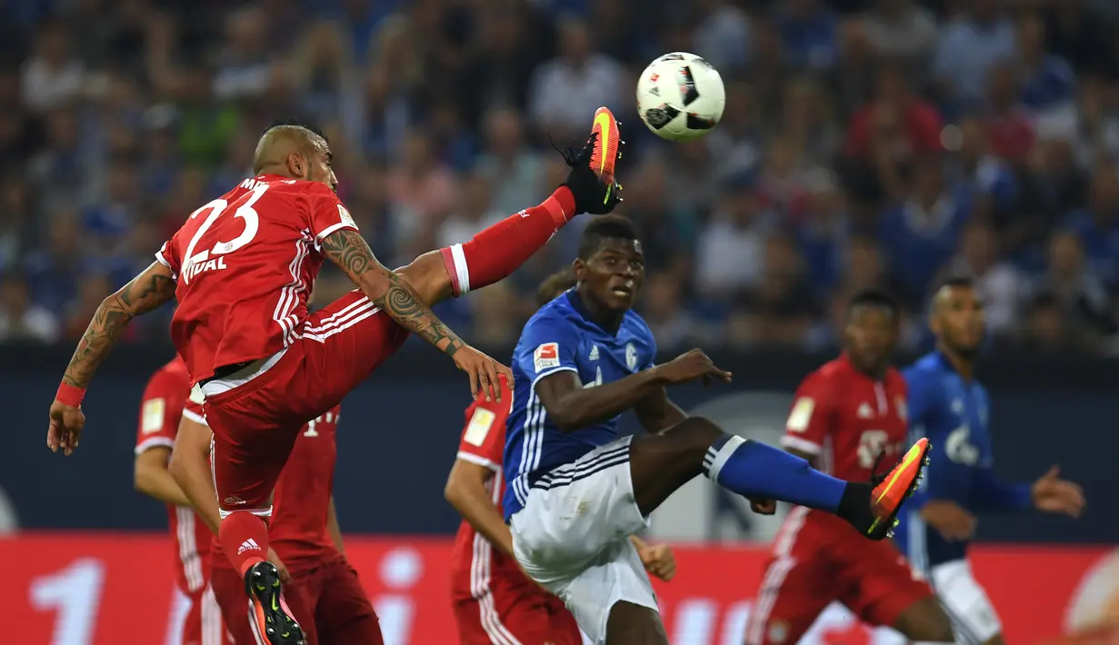 Pemain Bayern Munchen, Arturo Vidal, berebut bola dengan pemain Schalke 04, Abdul Rahman Baba, dalam lanjutan Bundesliga di Veltins Arena, Gelsenkirchen, Sabtu (10/9/2016) dini hari WIB. (AFP/Patrik Stollarz)