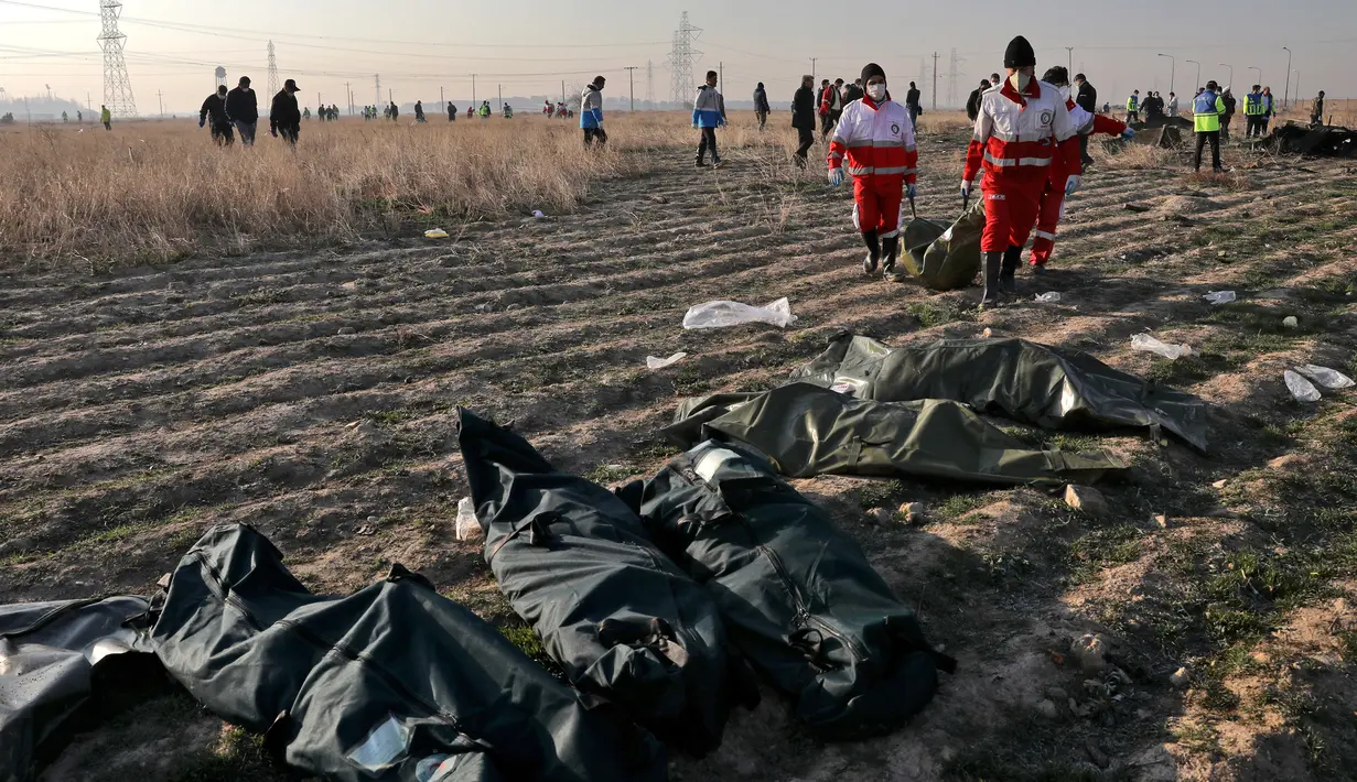 Tim penyelamat mengumpulkan jasad korban jatuhnya pesawat Boeing 737-800 di Shahedshahr, Iran, Rabu (8/1/2020). Pesawat sempat terbakar di udara sebelum akhirnya jatuh di lahan pertanian. (AP Photo/Ebrahim Noroozi)
