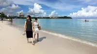 Pengunjung berjalan menyusuri tepi pantai Tumon di Guam, Kamis (10/8). Meskipun suasana ketegangan di kawasan itu meningkat  terkait ancaman bom nuklir Korea Utara, warga Guam tetap beraktivitas seperti biasa. (AP Photo/Tassanee Vejpongsa)