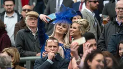 Dua racegoers terlihat berselfie saat menyaksikan Festival Grand National di arena Aintree, Liverpool, Inggris (7/4). Kehadiran racegoers memberikan nuansa tersendiri di kompetisi pacuan kuda terbesar tersebut. (AFP Photo / Oli Scarff)