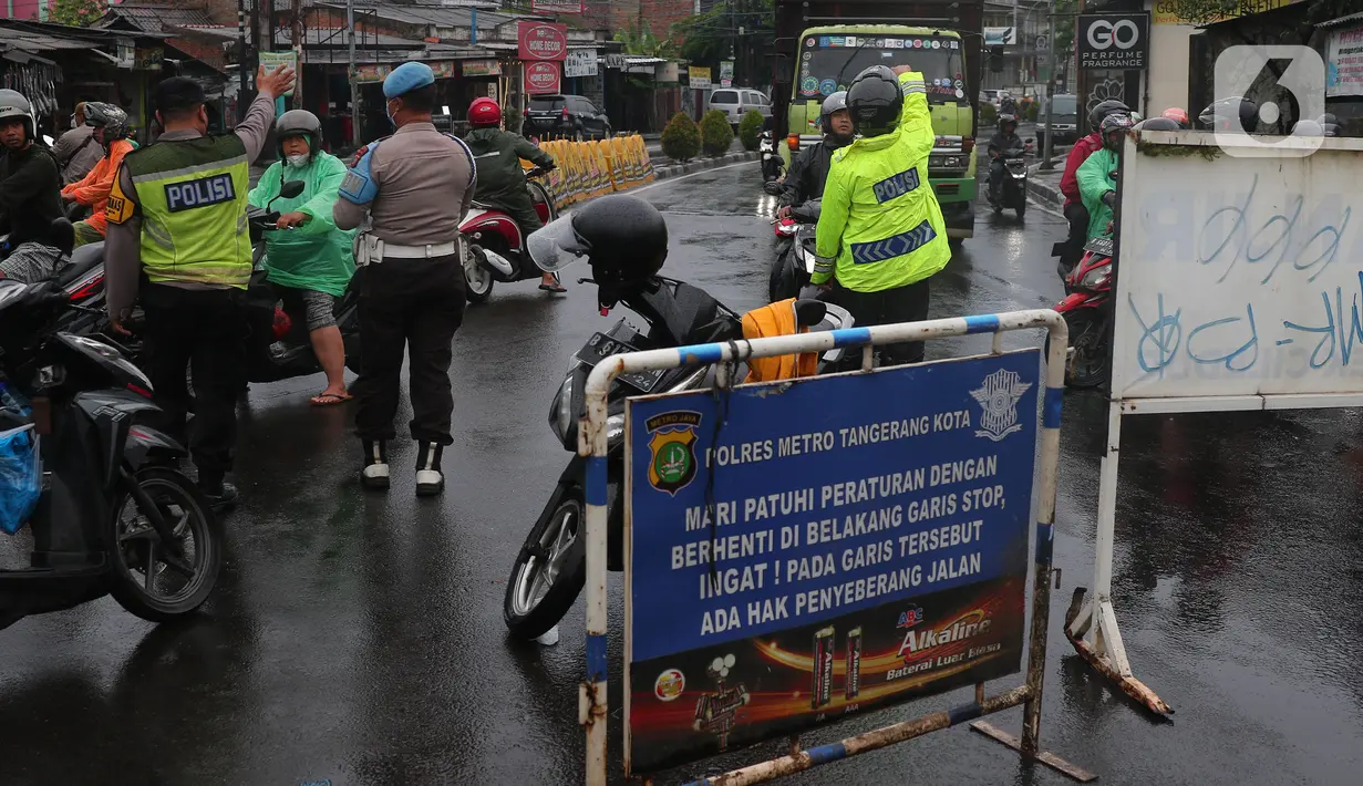 Petugas kepolisian melakukan penutupan jalan KH Hasyim Ashari, Kota Tangerang, Banten, Sabtu (16/7/2022). Akibat banjir yang merendam kawasan tersebut membuat petugas harus menutup jalur dan memutarbalikan para pengendara yang melintas. (Liputan6.com/Angga Yuniar)