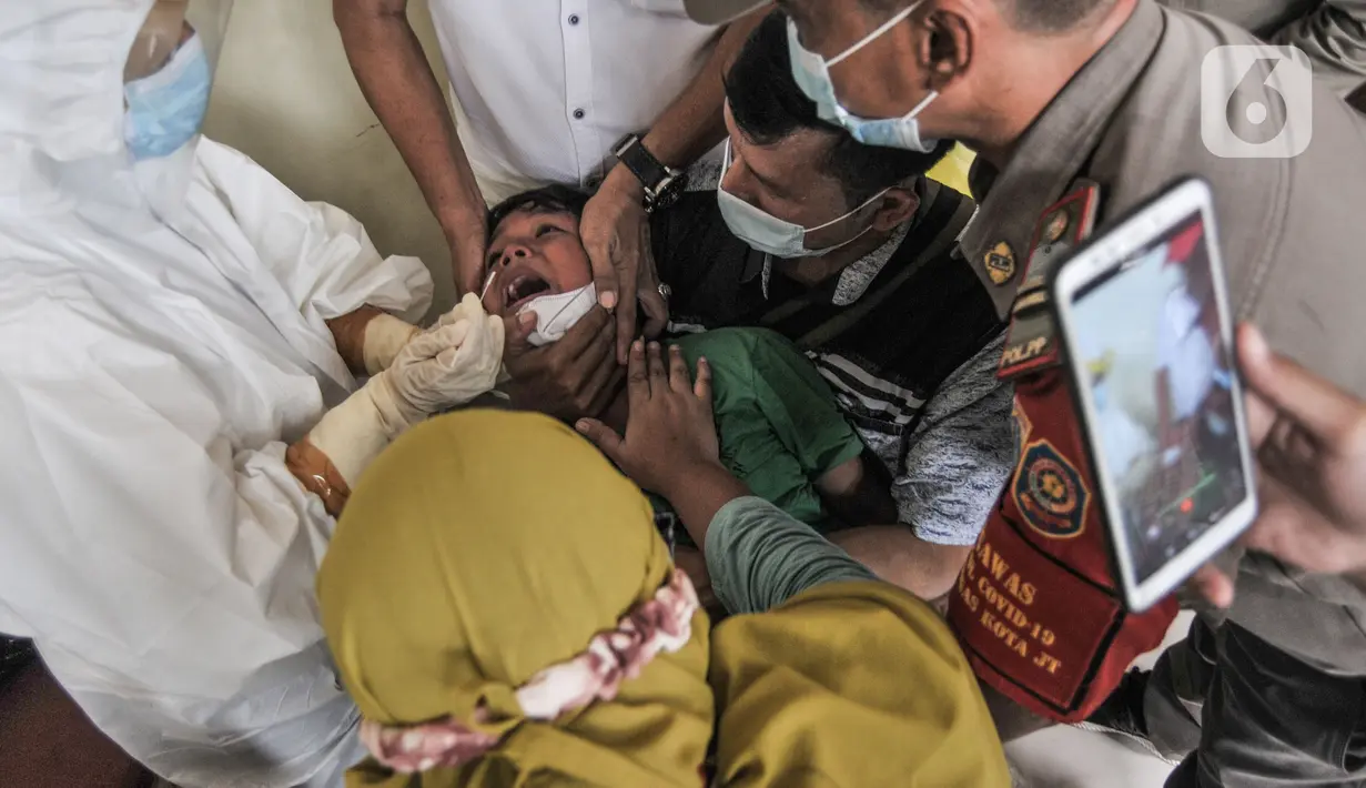 Orang tua mendampingi anaknya saat menjalani tes Covid-19 di GOR Kecamatan Makasar, Jakarta, Senin (17/5/2021). Pemkot Jakarta Timur menggelar tes Covid-19 gratis bagi warga yang baru tiba di Ibu Kota guna mencegah penyebaran virus Corona usai mudik. (merdeka.com/Iqbal S Nugroho)