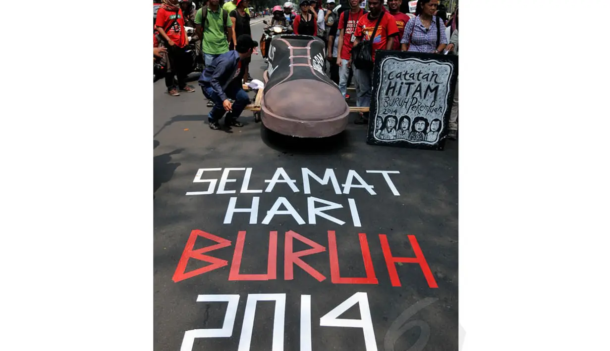 Di jalanan, menggunakan lakban massa membuat tulisan ucapan selamat hari buruh 2014, Kamis (1/5/14). (Liputan6.com/Johan Tallo)  