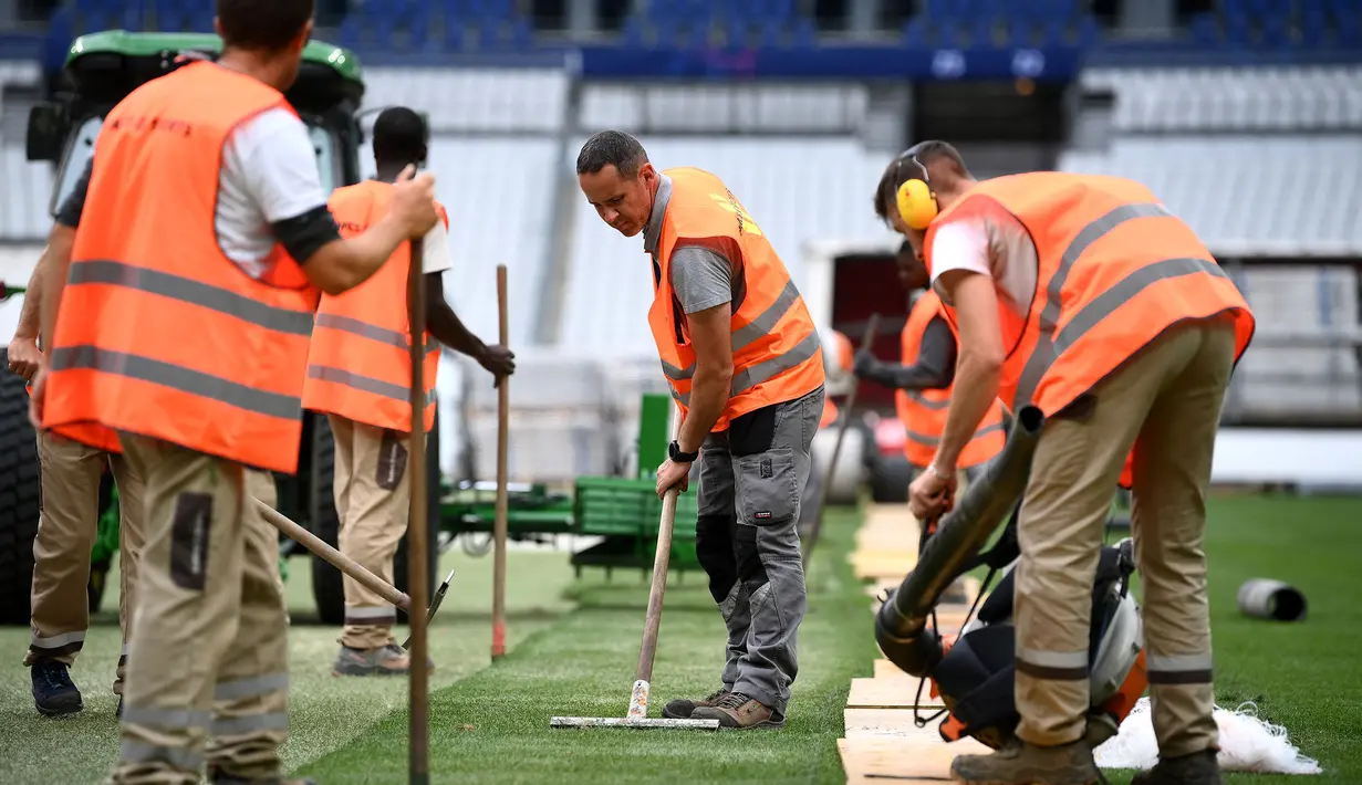 Sejumlah pekerja sedang memasang rumput hybrid baru di Stade de France, Saint-Denis, pada 24 Mei 2022 waktu setempat. Dalam waktu 48 jam, rumput baru yang ditanam di luar Barcelona, dipasang di Stade de France untuk pertandingan final Liga Champions antara Real Madrid dan Liverpool yang dijadwalkan berlangsung pada 28 Mei 2022. (AFP/Franck Fife)