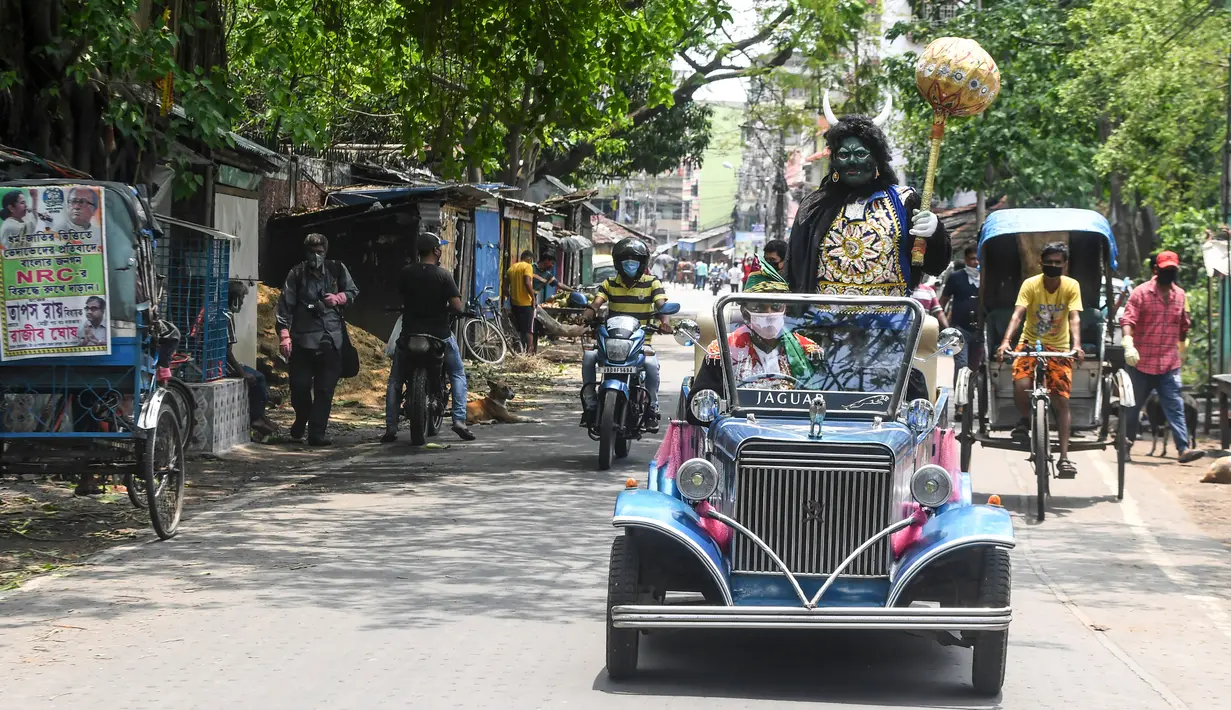 Aksi pria berkostum dewa kematian Yamaraj saat keliling kota menggunakan mobil klasik memberikan imbauan kepada warga soal bahaya wabah Covid-19  di tengah lockdown di Kota Kolkata, India (24/4/2020).  (AFP/Dibyangshu Sarkar)