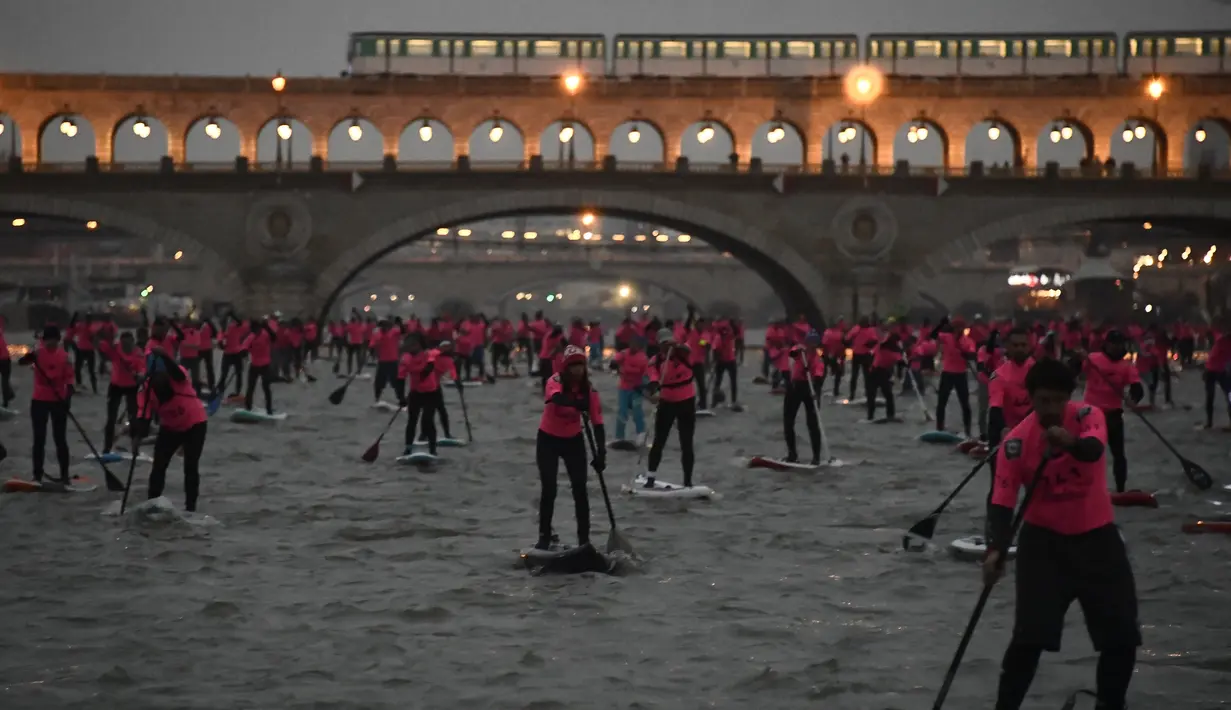 Para peserta ambil bagian dalam perlombaan dayung sambil berdiri pada Nautic SUP Paris di sepanjang sungai Seine, Paris, Prancis, Minggu (3/12). Nautic SUP Paris merupakan lomba dayung sambil berdiri terbesar di dunia. (AFP PHOTO/CHRISTOPHE SIMON)