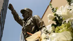 Karangan bunga terlihat di sebelah patung Fidel Castro setelah pengumuman kematiannya di Kedubes Kuba di Lima, Peru, Senin (28/11). Pemimpin revolusioner Kuba Fidel Castro meninggal dunia pada usia 90 tahun pada 25 November kemarin. (REUTERS/Mariana Bazo)
