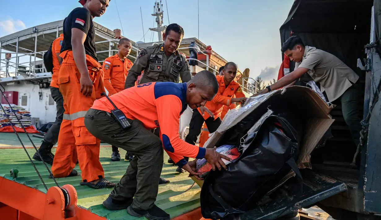 Distribusi ini dilakukan melalui jalur laut, dan udara, mengingat banyak akses jalan yang terputus. Tampak dalam foto, para relawan menurunkan bantuan untuk korban banjir bandang di permukiman warga Banda Aceh, Provinsi Aceh, pada 1 Desember 2025. (Chaideer MAHYUDDIN/AFP)