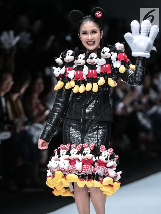 Artis Sandra Dewi berjalan di 'catwalk' mengenakan busana kolaborasi antara Disney dan Matahari pada Jakarta Fashion Week 2019 di Senayan City, Selasa (23/10). Sandra Dewi mengenakan busana dengan ornamen boneka Mickey Mouse. (Liputan6.com/Faizal Fanani)