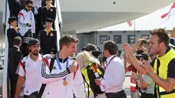 Pemain depan Timnas Jerman, Thomas Mueller, memberikan acungan jempol kepada para suporter sesaat setelah mendarat di Bandara Tegel, Berlin, (15/7/2014). (REUTERS/Karina Hessland/Pool)