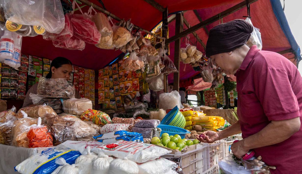 Seorang pembeli (kanan) sedang memilih bahan makanan mentah di sebuah warung pasar tradisional di Jakarta pada Rabu 3 Juni 2026. (BAY ISMOYO/AFP)