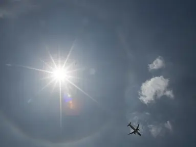 Pesawat komersil melintas dilatari fenomena halo matahari di Meksiko, Sabtu (7/7). Fenomena halo matahari terjadi karena pembiasan kristal es yang berada di sekitar matahari sehingga membentuk cincin pelangi yang mengelilingi matahari (AP/Moises Castillo)