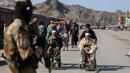 Seorang personel keamanan Taliban berjaga-jaga ketika anak laki-laki Afghanistan membantu pria lanjut usia di kursi roda setelah insiden baku tembak antara pasukan perbatasan Afghanistan dan Pakistan di dekat perbatasan Torkham yang melintasi antara Afghanistan dan Pakistan, di provinsi Nangarhar pada 20 Februari 2023. Penyeberangan utama di perbatasan Afghanistan-Pakistan tetap ditutup pada Selasa, 21 Februari 2023, untuk hari ketiga berturut-turut, kata para pejabat. (Shafiullah KAKAR / AFP)