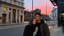 Menikmati senja kota, Anisha mengenakan long coat hitam dipadukan inner kemeja abu-abu. Sedangkan suaminya mengenakan jaket coklat dengan inner kaos hitam.  [@tmski]